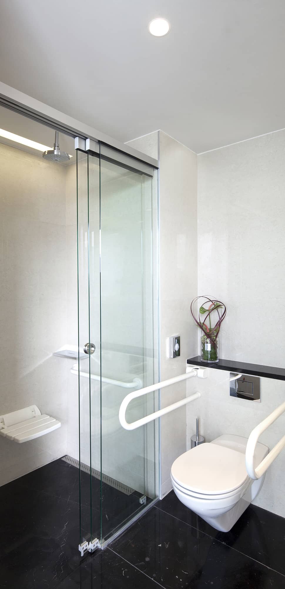 Barrierefreies Bad – bodenebene Dusche mit Klappsitz und Haltegriffen sowie WC mit Stützgriffen für barrierefreien Umbau
