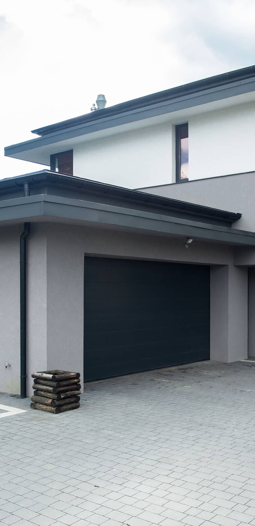 Garage bauen – modernes Einfamilienhaus mit anthrazitfarbenem Sektionaltor und gepflasterter Einfahrt